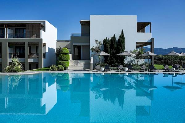 Außenbereich des Pelagos Suites Hotel & Spa mit großem Pool und Sonnenliegen