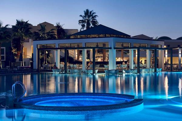 Der Außenpool des Pelagos Suites Hotel & Spa bei Nacht mit beleuchteter Bar.