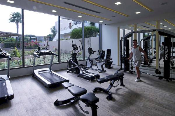 Fitnessstudio im Pelagos Suites Hotel & Spa mit modernen Geräten und großer Fensterfront.