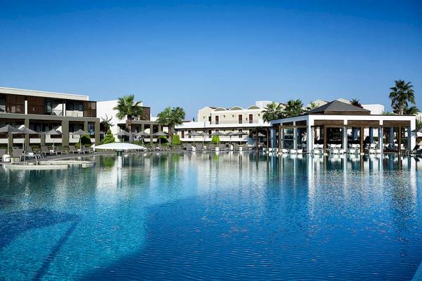 Außenbereich des Pelagos Suites Hotel & Spa mit großem Pool und Sonnenliegen.