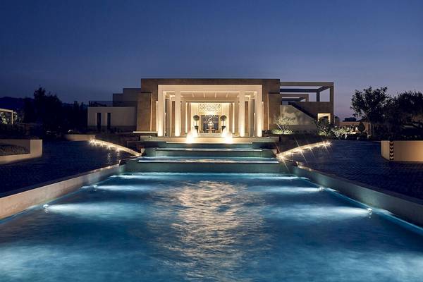 Nachtansicht des Pelagos Suites Hotel & Spa mit beleuchtetem Pool und Eingangsbereich