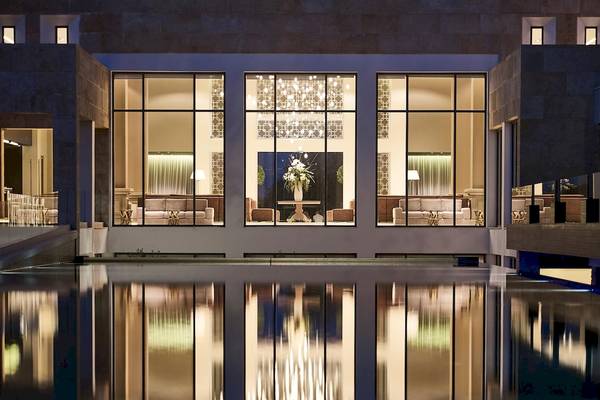 Außenansicht des Pelagos Suites Hotel & Spa bei Nacht mit großen Fenstern und Innenbeleuchtung.