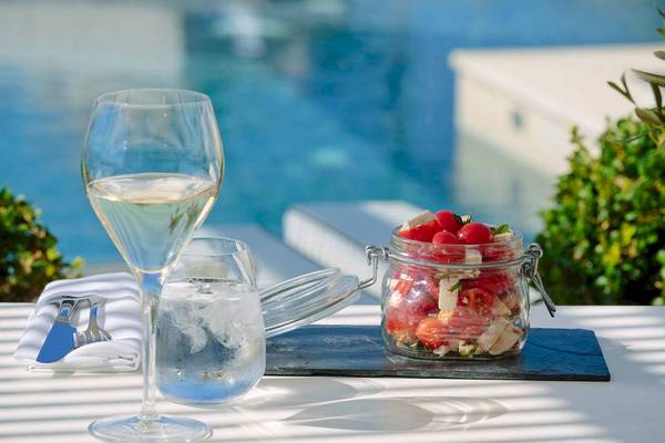 Ein Glas Wein und eine Schüssel Salat stehen auf einem Tisch am Pool