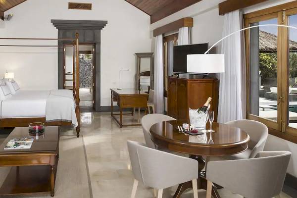 Innenansicht der Suite im Melia Salinas Hotel mit großem Bett, Wohnzimmerbereich und Esstisch.