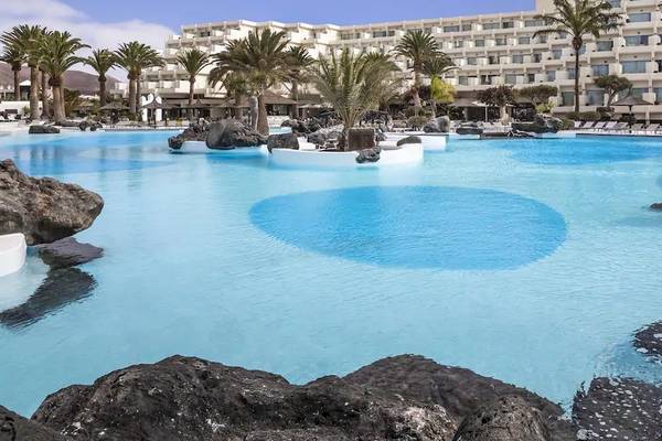 Außenpool des Melia Salinas Hotels mit Felsen und Palmen