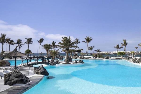 Außenbereich des Melia Salinas Hotels mit Swimmingpool, Liegestühlen und Palmen