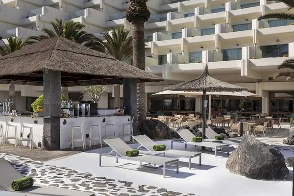 Außenbereich des Melia Salinas Hotels mit Bar, Liegestühlen und Sonnenschirmen.