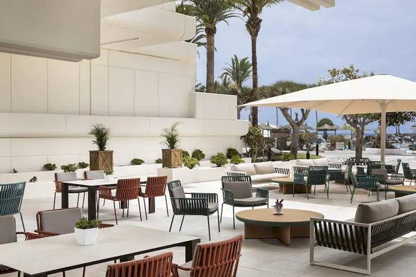 Außenterrasse des Melia Salinas Hotels mit Tischen, Stühlen und Sonnenschirmen.