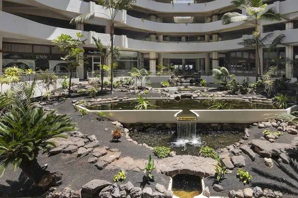 Innenhof des Melia Salinas Hotels mit Brunnen, Pflanzen und gepflastertem Boden.