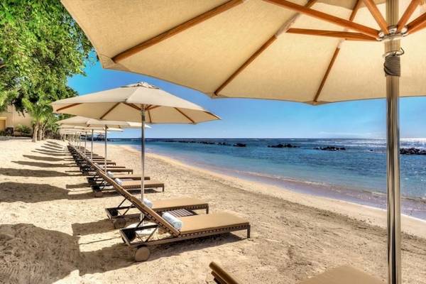 Strandliegen am Westin Turtle Bay Resort & Spa, Mauritius, mit Sonnenschirmen und Blick auf das Meer.