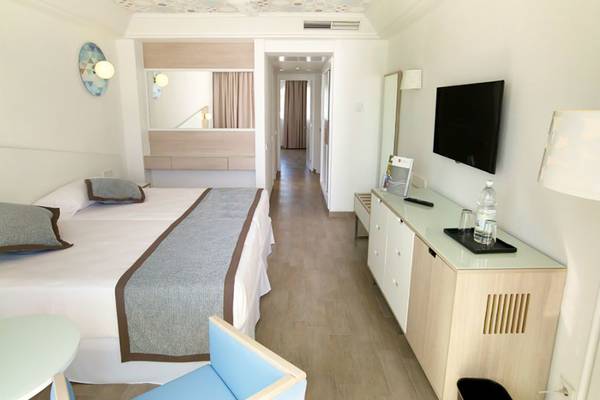 Innenansicht eines Hotelzimmers im Riu Gran Canaria mit Doppelbett, Fernseher und moderner Einrichtung.
