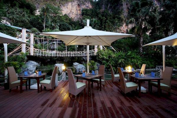 Außenbereich des Centara Grand Beach Resort & Villas Krabi mit Tischen und Stühlen unter großen Schirmen.