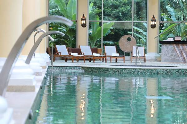 Pool-Lounge-Bereich im Iberostar Grand Paraiso Hotel mit Holzliegen und Pflanzen im Hintergrund.
