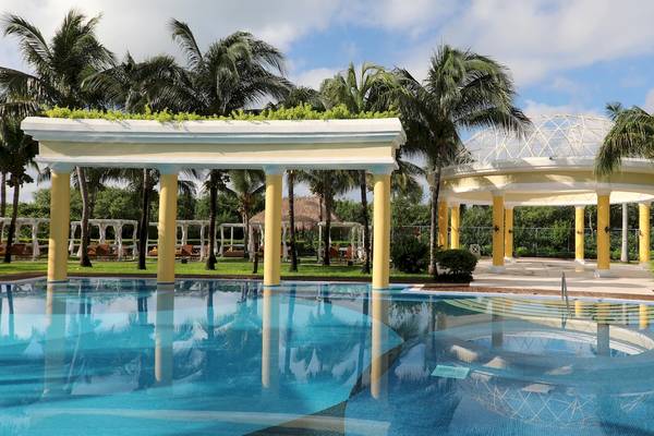 Außenbereich des Iberostar Grand Paraiso Hotels mit Swimmingpool, Gazebo und Palmen.