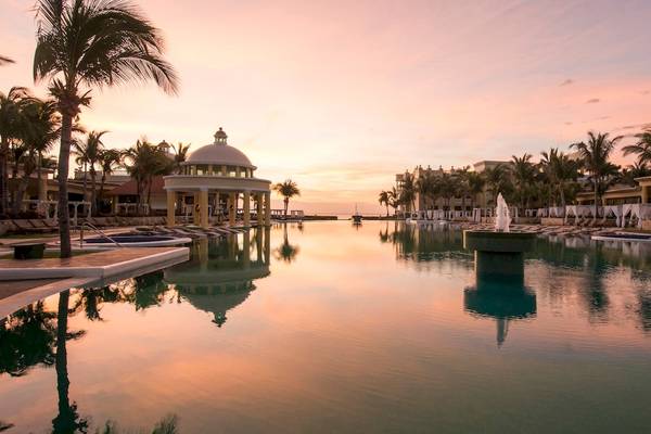Iberostar Grand Paraiso Pool bei Sonnenuntergang mit Palmen und einem Brunnen
