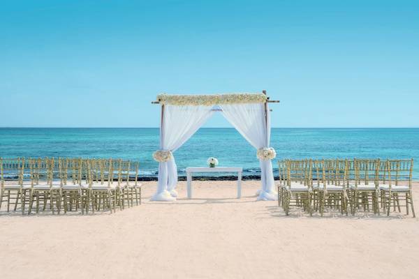 Hochzeitszeremonie am Strand des Iberostar Grand Paraiso mit weißen Vorhängen und Blumendekoration.