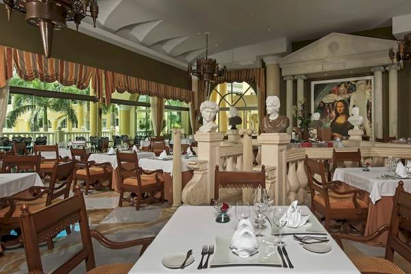 Innenansicht des Speisesaals im Iberostar Grand Paraiso Hotel mit Tisch, Stühlen und Dekorationen.