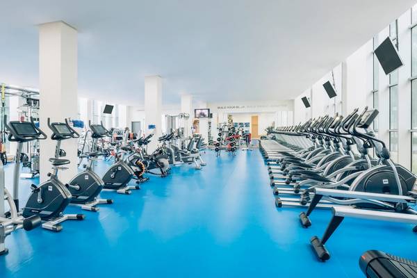 Fitnessstudio im Iberostar Grand Paraiso Hotel mit vielen Cardiogeräten und blauen Boden