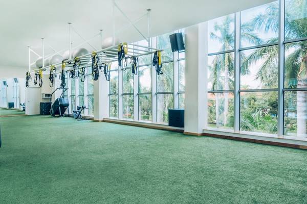 Fitnessstudio im Iberostar Grand Paraiso Hotel mit Blick auf Palmen und Außenbereich.