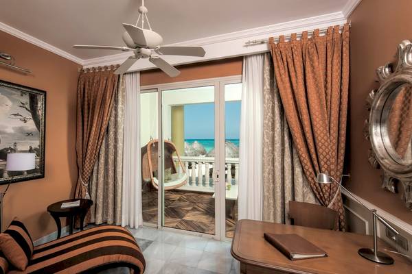 Hotelzimmer im Iberostar Grand Paraiso mit Meerblick, Loungemöbeln und Gemälde.