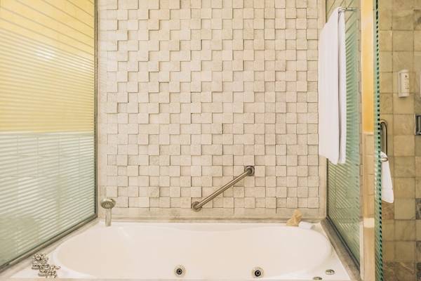 Badezimmer im Iberostar Grand Paraiso mit Badewanne, Handläufen und Fliesenwänden.