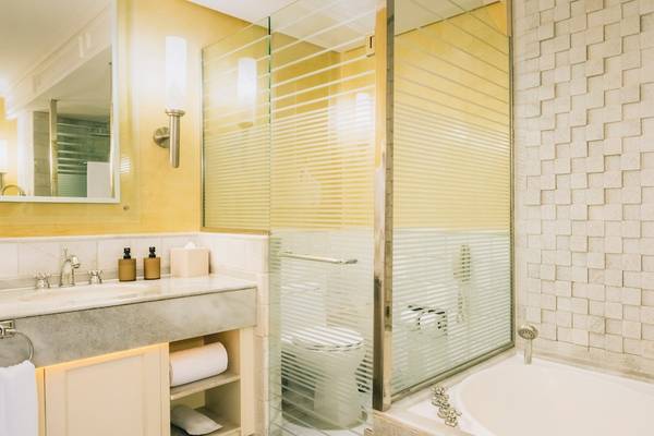 Badezimmer im Iberostar Grand Paraiso Hotel mit gelben Wänden, Marmorboden, Badewanne, Dusche und Toilette.