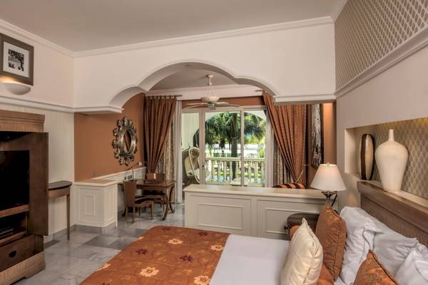Innenansicht eines Hotelzimmers im Iberostar Grand Paraiso, mit Bett, Fernseher und Balkon.