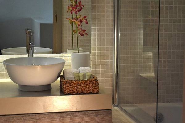 Das Badezimmer im Bay Hotel & Suites mit einem Waschbecken, Handtüchern und einem Korb mit Pflegeprodukten.