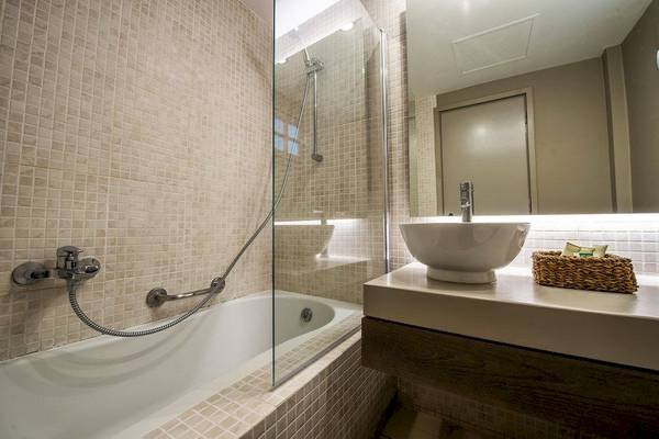 Badezimmer im Bay Hotel & Suites mit Badewanne, Glasdusche und Waschbecken