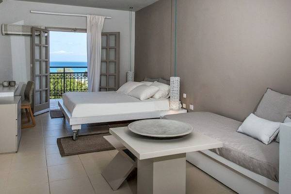 Zimmer im Bay Hotel mit Balkon, zwei Betten, Schreibtisch, Fernseher, und Blick auf das Meer.