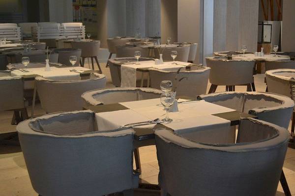 Innenansicht des Restaurants im Bay Hotel & Suites mit gedeckten Tischen und Stühlen.