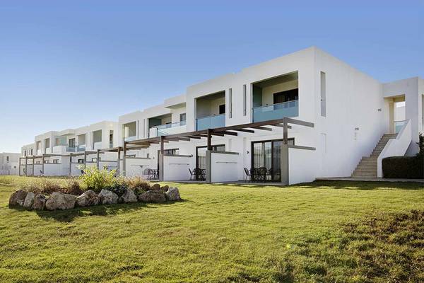 Außenansicht des Club Plimmiri Hotels mit weißen Gebäuden und grünem Rasen