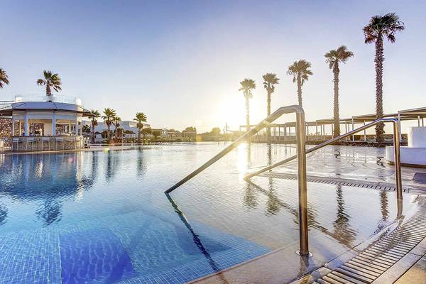 Sonnenuntergang am Pool des Club Plimmiri Hotels mit Palmen und einer Bar im Hintergrund.