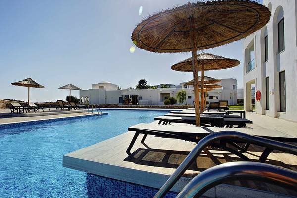 Außenpoolbereich des Club Plimmiri Hotels mit Sonnenliegen und Sonnenschirmen