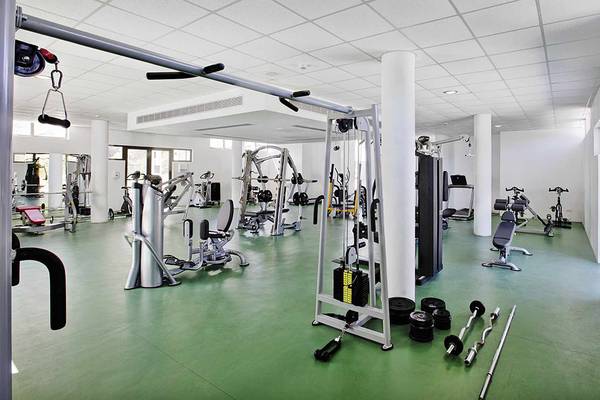 Fitnessstudio im Club Plimmiri Hotel mit verschiedenen Trainingsgeräten und grün glänzendem Boden.