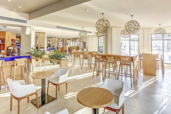Innenbereich des Club Plimmiri Hotels mit Tischen, Stühlen und Pflanzen.