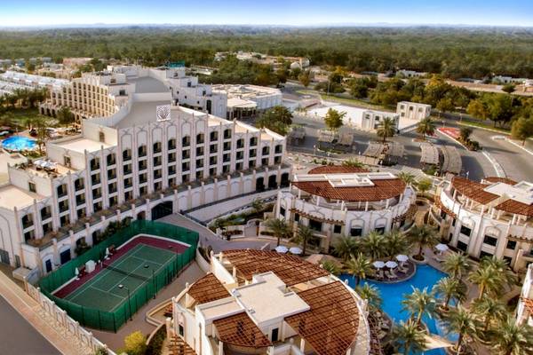 Luftaufnahme des Al Ain Rotana Hotels mit Tennisplatz, Swimmingpool und mehreren Gebäuden.