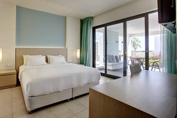 Innenansicht eines Hotelzimmers im Club Plimmiri Hotel mit Bett, Nachttischen und einer Terrasse davor.