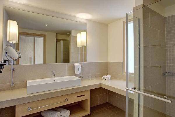 Badezimmer im Club Plimmiri Hotel mit Spiegel, Waschbecken, Dusche und Handtüchern.
