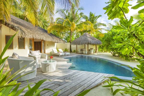 Außenbereich des Outrigger Maldives Maafushivaru Resorts mit Pool und Loungemöbeln.