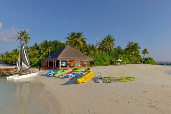 Strand im Outrigger Maldives Maafushivaru Resort mit Booten und einer Hütte