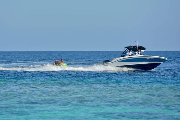 Zwei Leute auf Wasserski hinter einem Boot im Meer