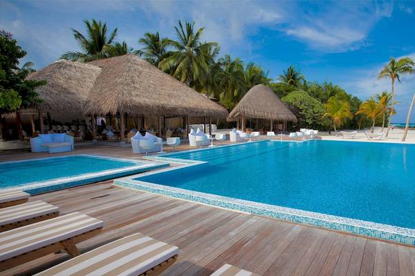 Außenpool des Outrigger Maldives Maafushivaru Resort mit Liegestühlen und Sonnenschirmen.
