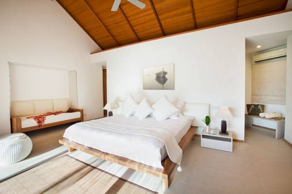Schlafzimmer im Outrigger Maldives Maafushivaru Resort mit Bett, Couch, Nachttisch und Klimaanlage