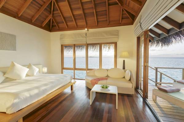 Innenansicht eines Zimmers im Outrigger Maldives Maafushivaru Resort mit Blick auf das Meer.