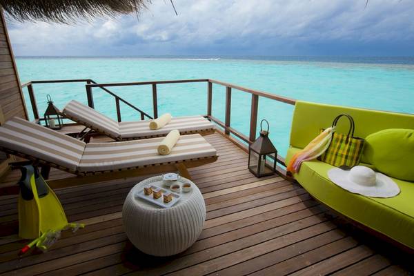 Ein Balkon mit Blick auf das Meer, zwei Sonnenliegen, ein Tisch mit Snacks und eine grüne Couch.