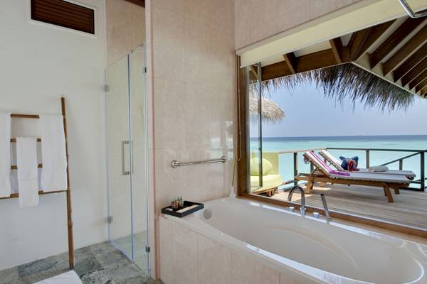 Badezimmer des Outrigger Maldives Maafushivaru Resort mit Badewanne und Meerblick.