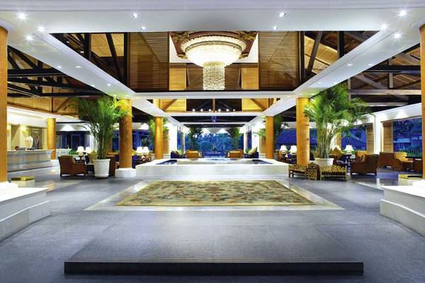 Empfangshalle des Laguna Hotels mit einem zentralen Teppich, umgeben von Pflanzen und Möbeln, mit einer großen Lampe an der Decke.