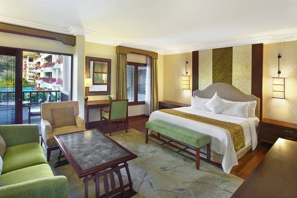 Innenansicht einer Luxus Suite im Laguna Hotel mit Bett, Sofa, Tisch und Blick auf den Pool.