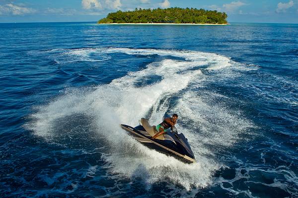 Ein Mann fährt mit einer Jet-Ski auf dem Ozean vor Kurumba Maldives.